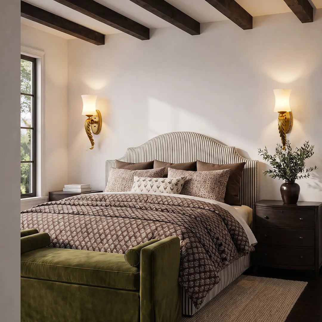 Pair of vintage brass wall sconces flanking a bed in a cozy bedroom with exposed ceiling beams.