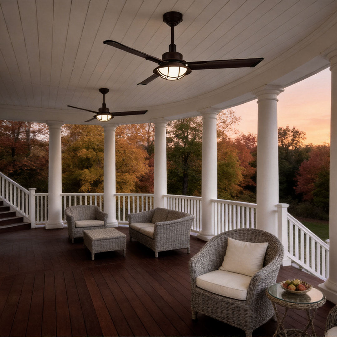 Vintage ceiling fans with lights illuminating a spacious wraparound porch at dusk.