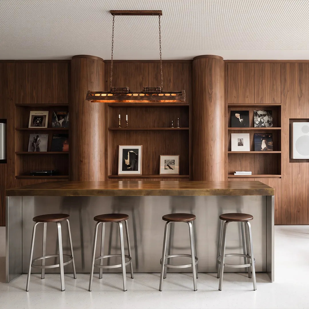 Vintage farmhouse chandelier installed above a bar counter with warm linear lighting.
