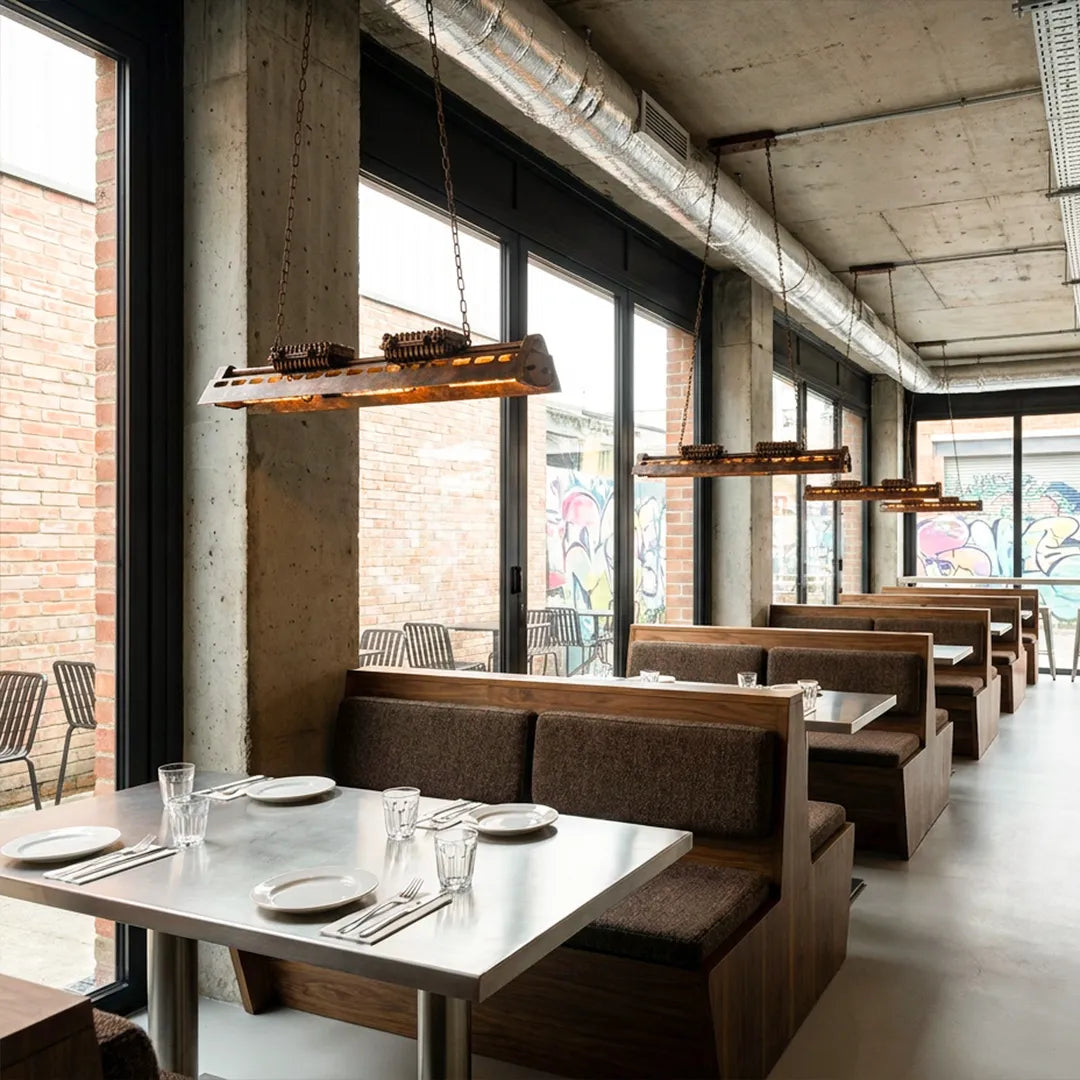 Vintage farmhouse chandelier installed above restaurant seating with an elongated metal frame.