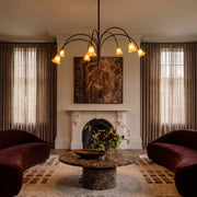 Vintage flower chandelier hanging above a cozy living room with a fireplace, curved arms, and tulip-style glass shades.