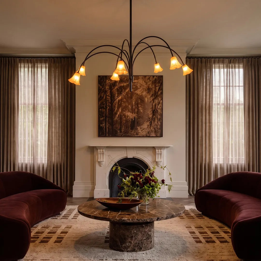 Vintage flower chandelier hanging above a cozy living room with a fireplace, curved arms, and tulip-style glass shades.