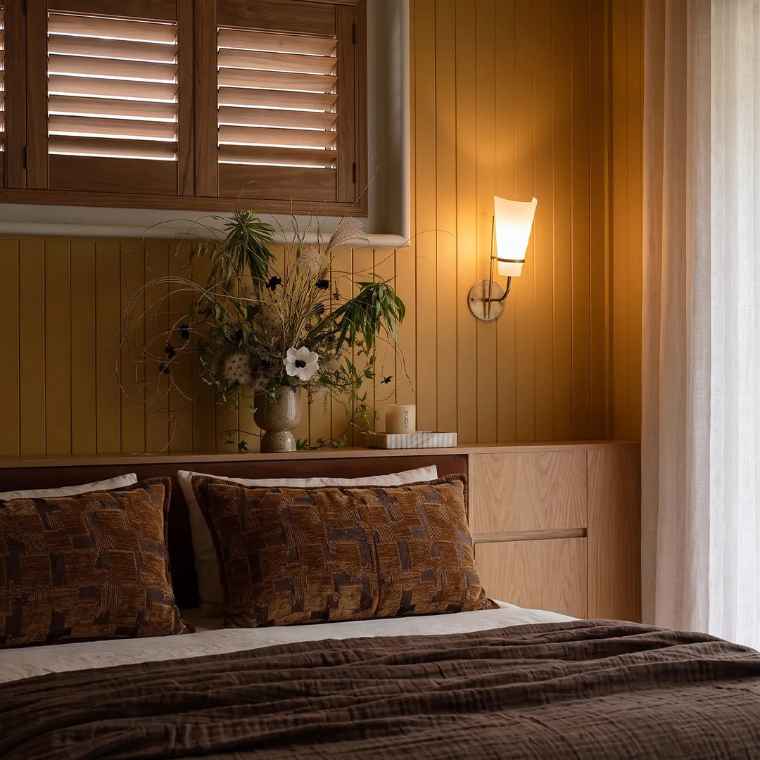 Vintage French wall lights styled above a bedside table with warm ambient lighting and a classic brass finish.
