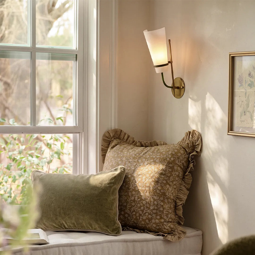 Vintage French wall lights mounted beside a window and accent chair with a soft frosted glass shade.