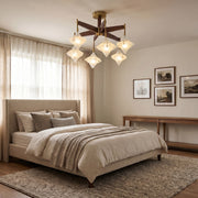 Vintage gold chandelier with crystal-inspired glass shades installed in a cozy bedroom with neutral decor.