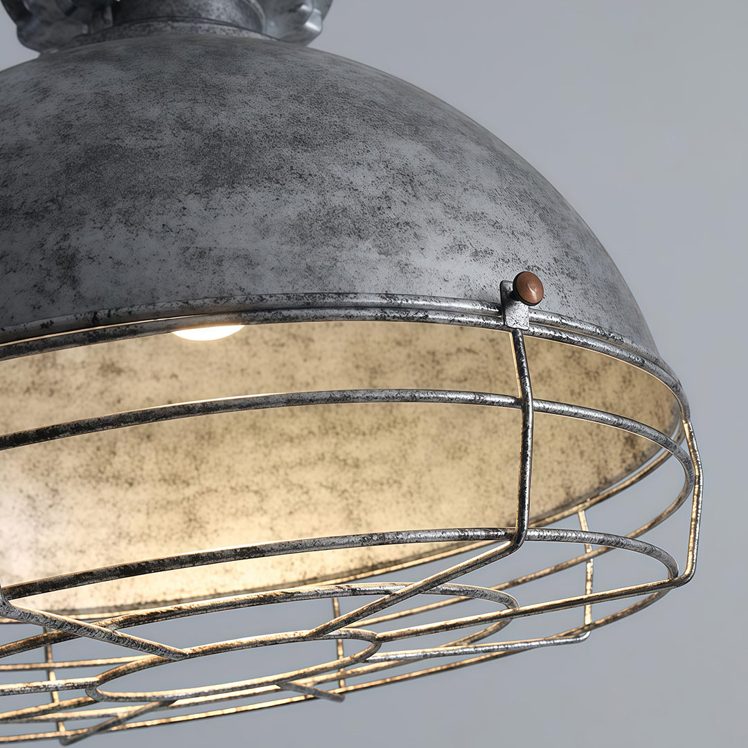 Close-up detail of vintage industrial pendant lighting showing distressed metal dome and decorative cage construction