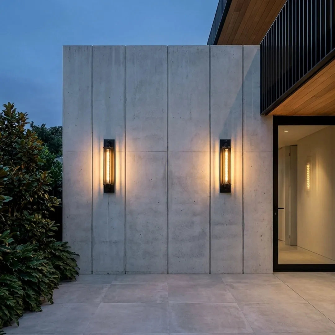 Vintage industrial wall sconces installed on a modern concrete exterior wall beside a contemporary entrance.