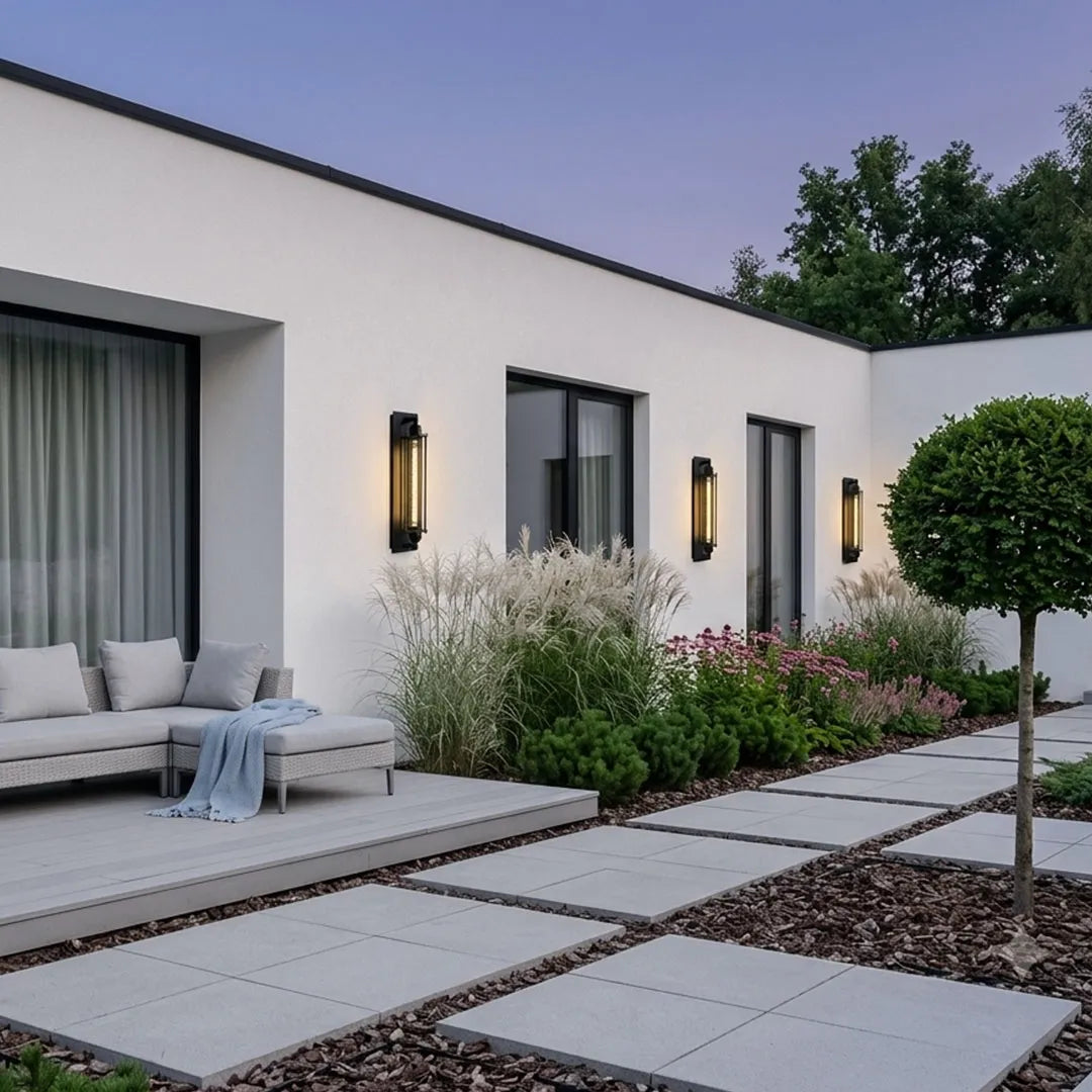 Vintage industrial wall sconces arranged along a white modern house exterior beside a landscaped walkway.