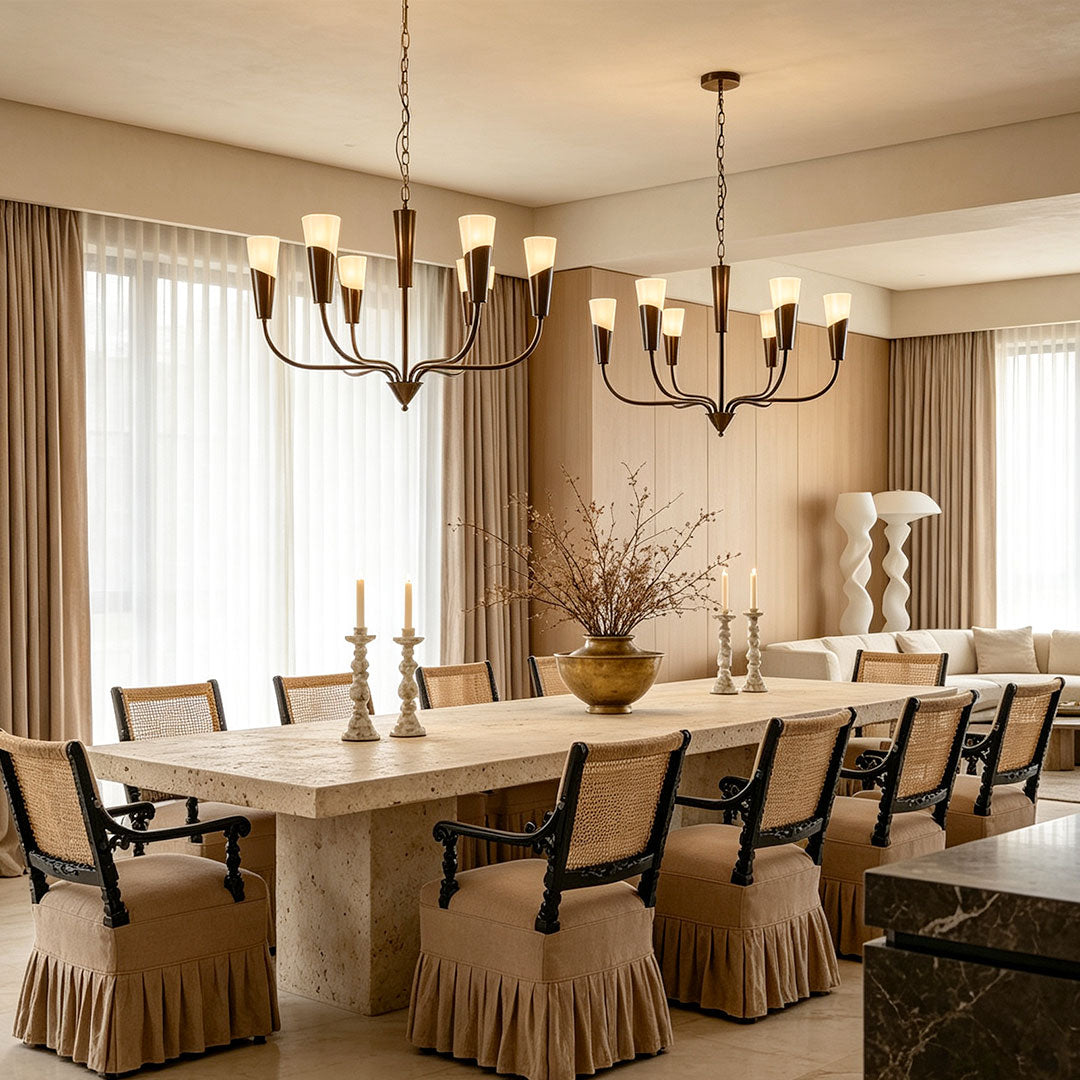 Vintage Italian chandeliers hanging above a long stone dining table with upholstered chairs.
