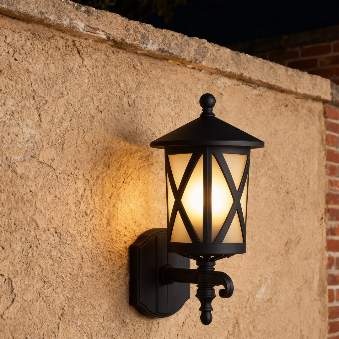 Vintage outdoor black wall light glowing warmly on rough stucco surface at dusk