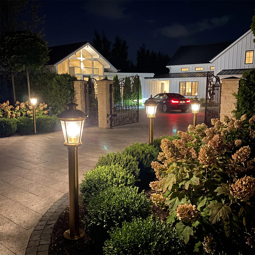 Vintage outdoor bollard lights with warm glow along home driveway at night