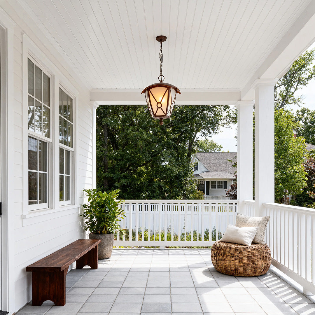 Vintage style outdoor LED pendant light casting glow on white covered porch with wicker furniture