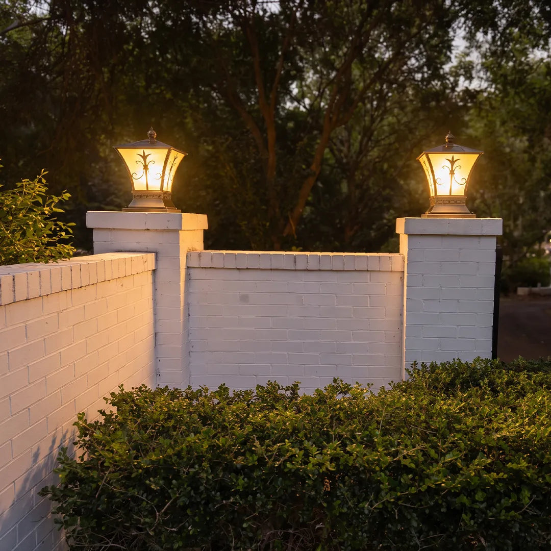Vintage outdoor pillar lights with warm glow on white brick gate columns