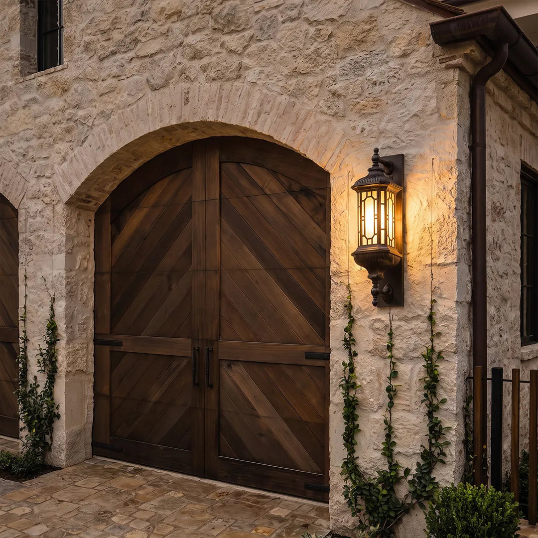 Vintage outdoor wall lantern mounted beside an arched wood entry door on a stone exterior wall.