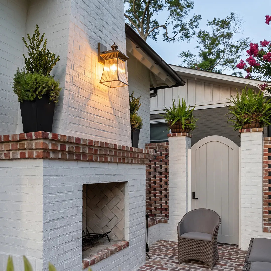 Vintage outdoor wall lantern illuminating white brick patio and outdoor fireplace