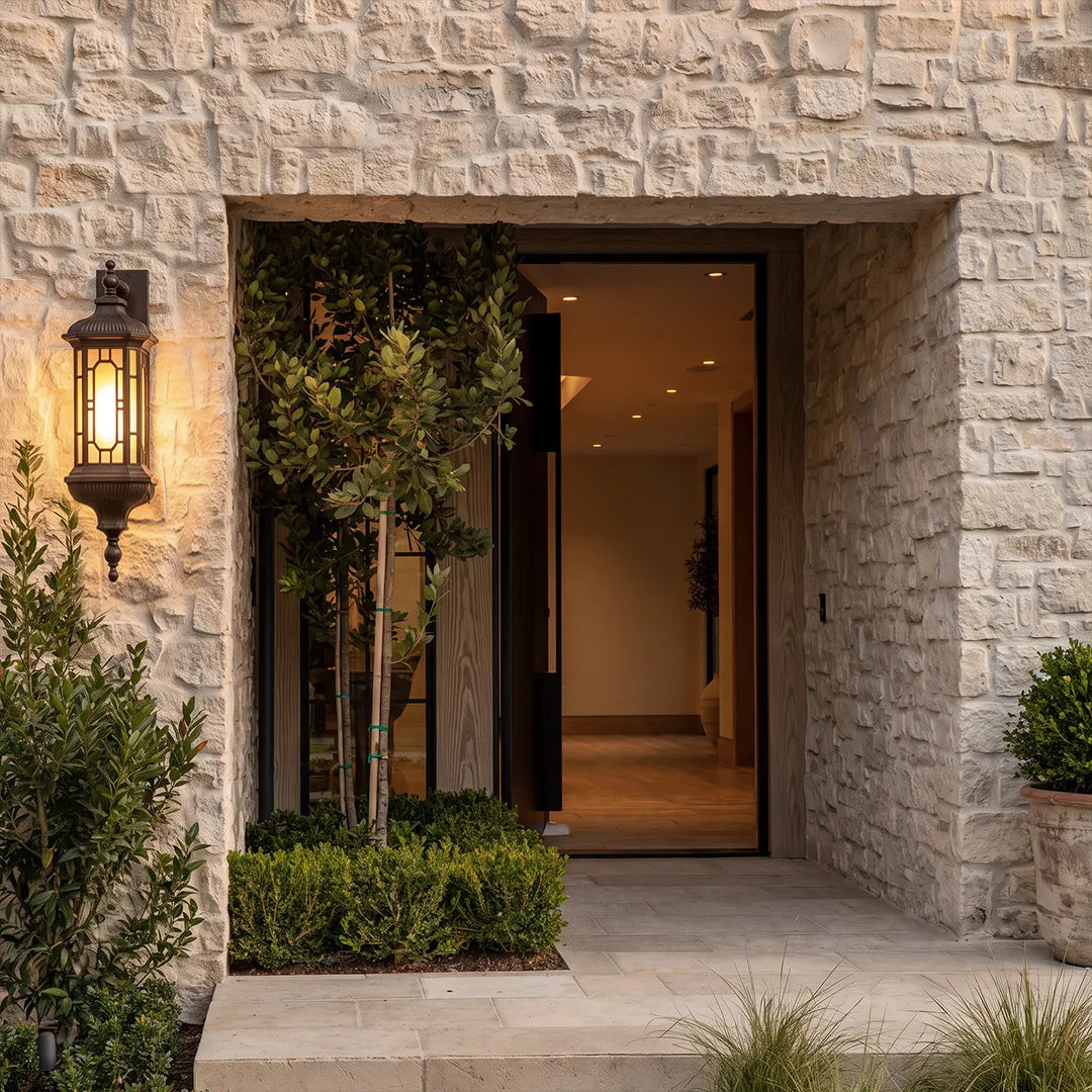 Vintage outdoor wall lantern mounted beside a modern front entry framed by textured stone walls.