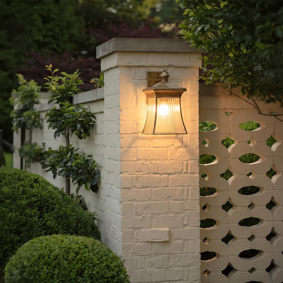 Vintage outdoor wall lantern with warm glow on white brick garden wall