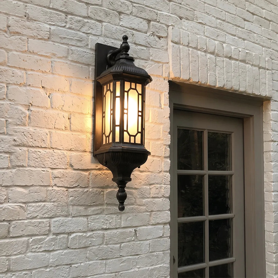 Vintage outdoor wall lantern installed on a white brick wall beside a dark-framed exterior window.