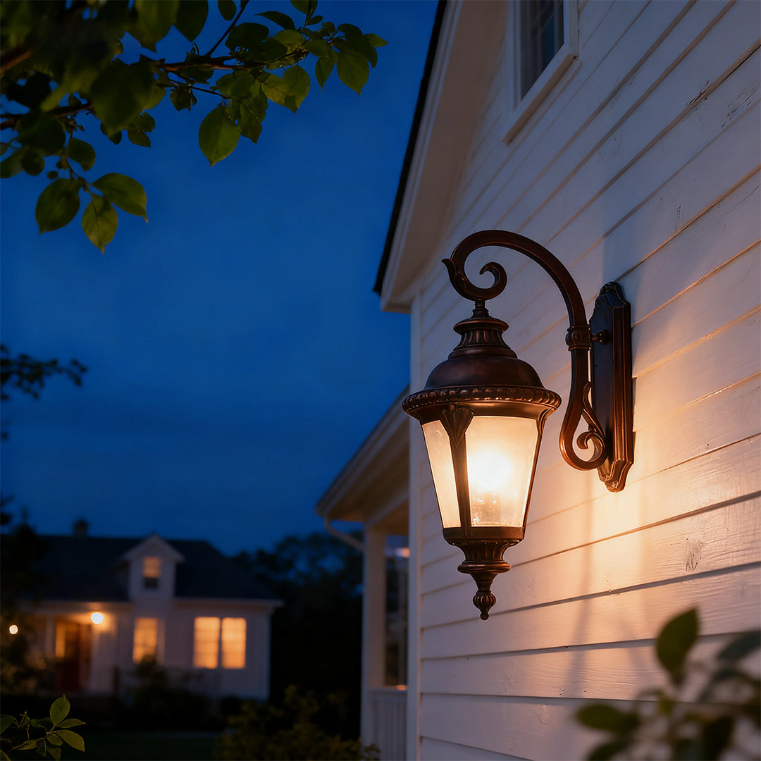 Vintage outdoor wall sconce brightening white home exterior at twilight with blue sky backdrop