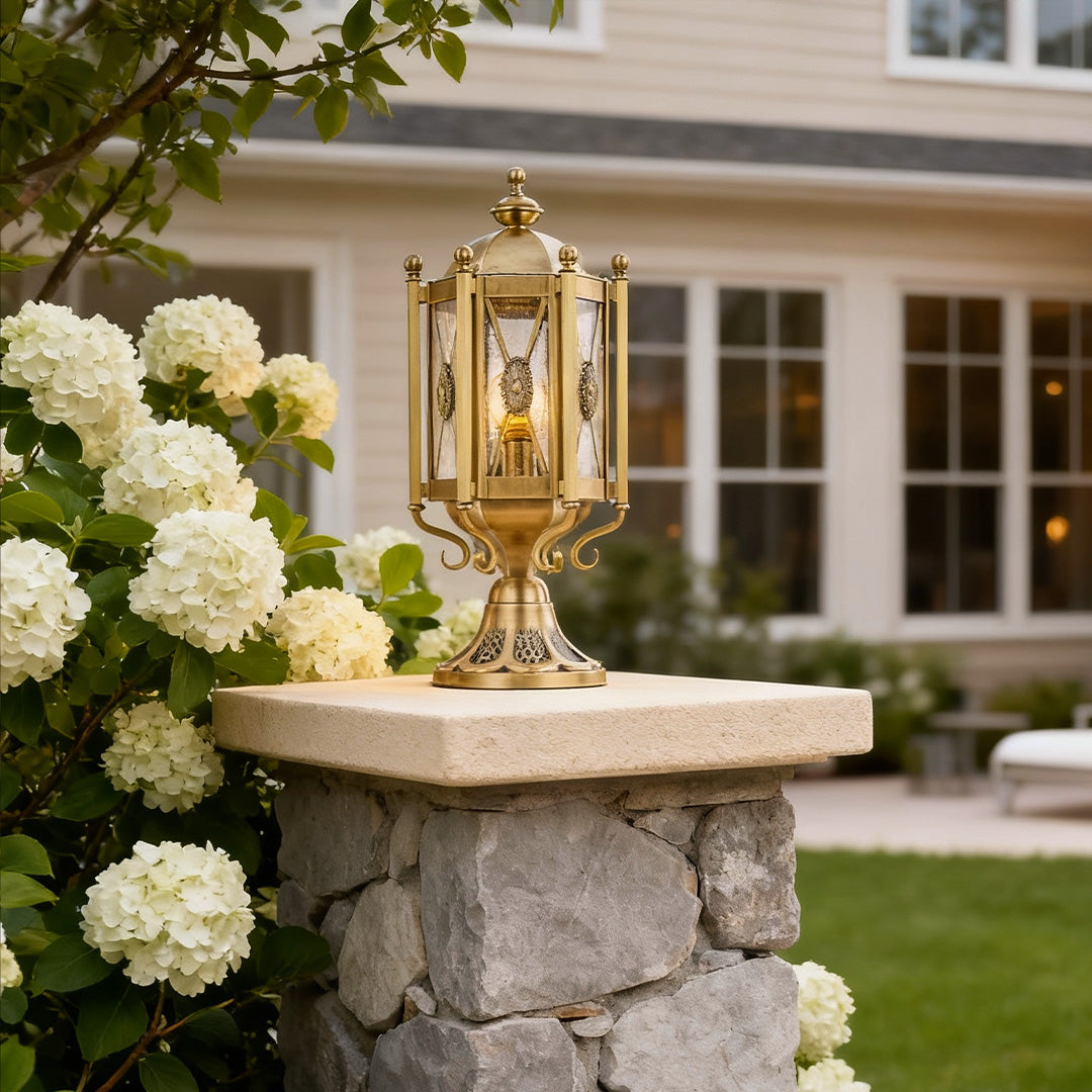 Vintage pillar lights adding elegance to a stone wall, surrounded by lush greenery and white flowers.