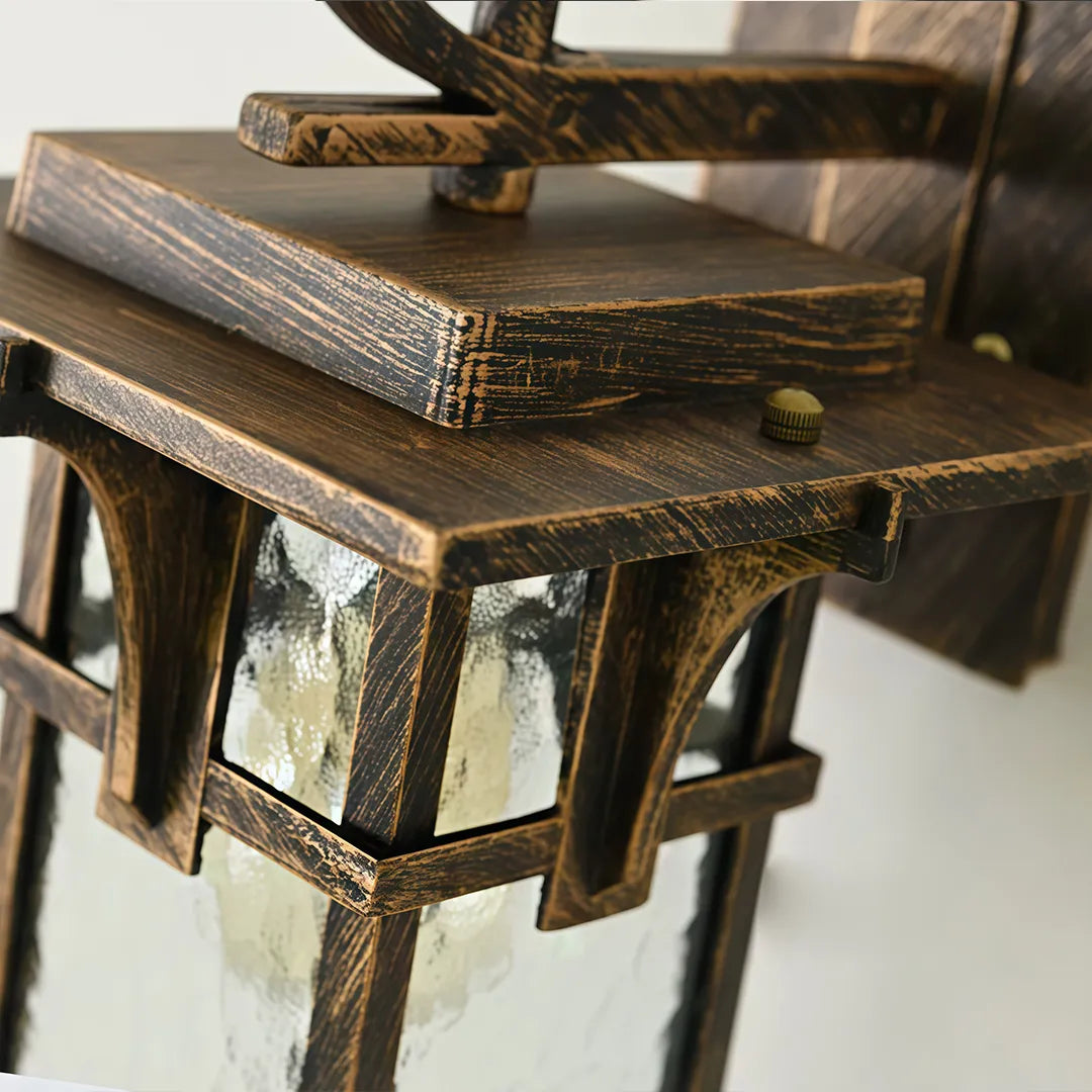 Vintage sconce wall light close-up showing the sculpted bronze backplate and elegant curved mounting arm.