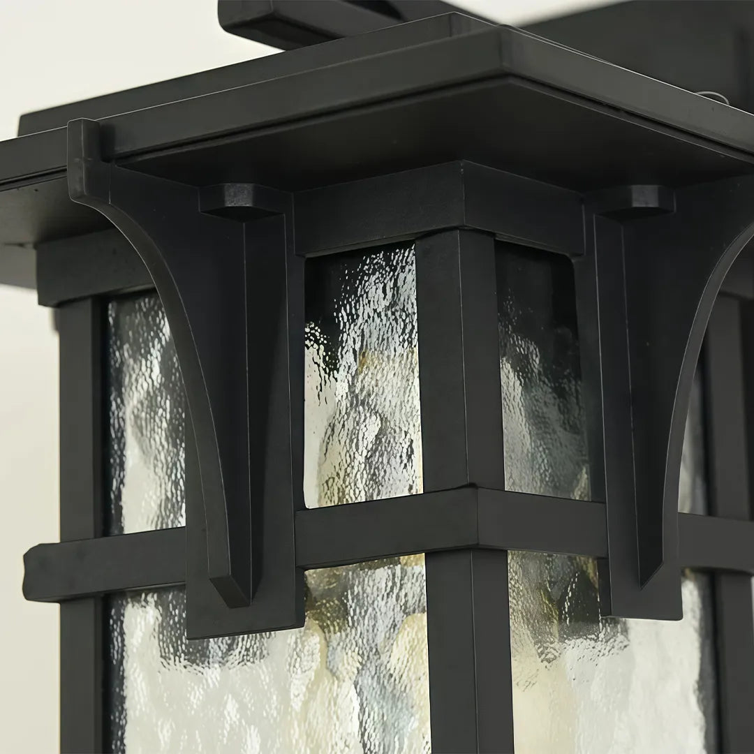 Vintage sconce wall light close-up showing decorative metal framing and textured clear glass panels.