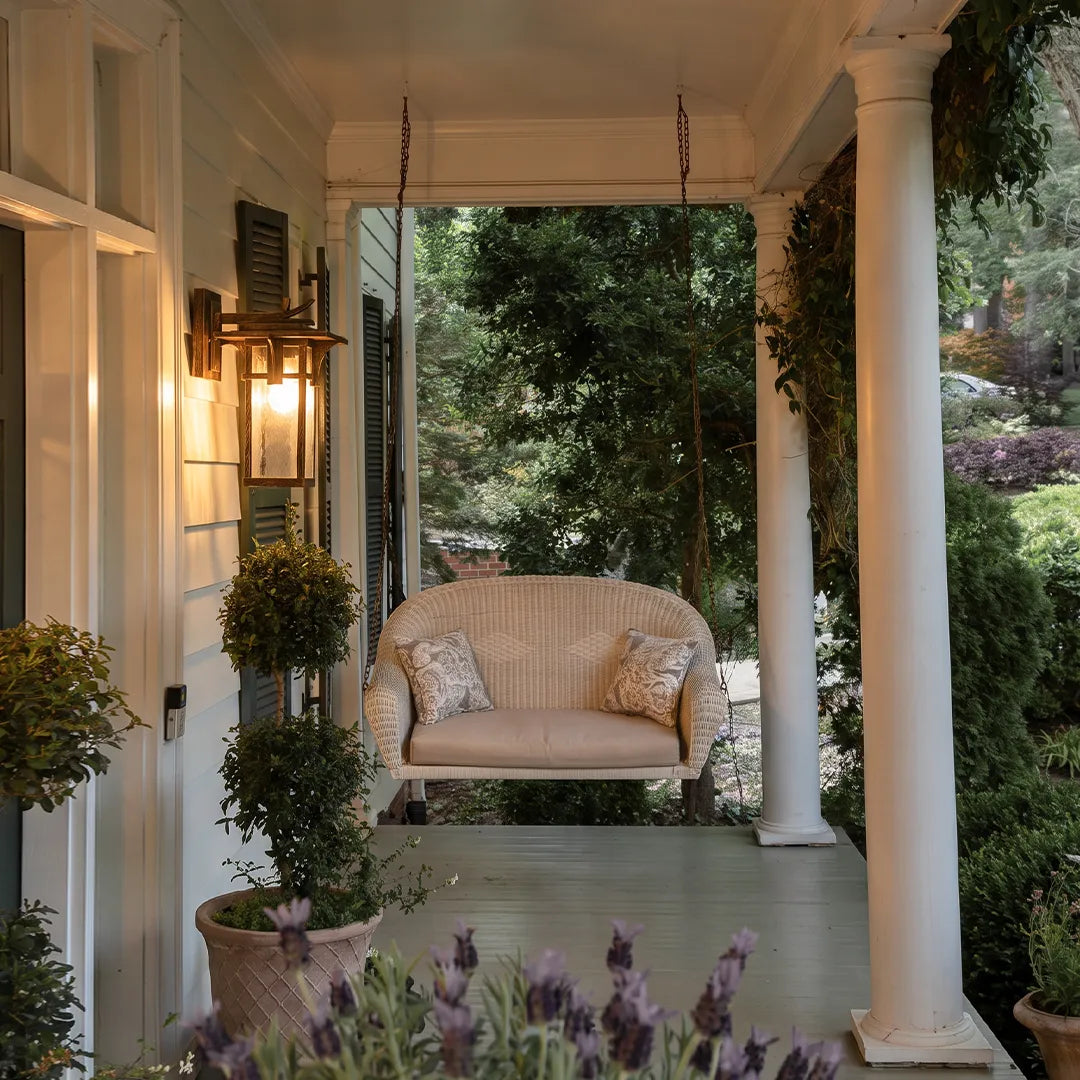Vintage sconce wall light mounted on an outdoor column beside a comfortable patio seating area.