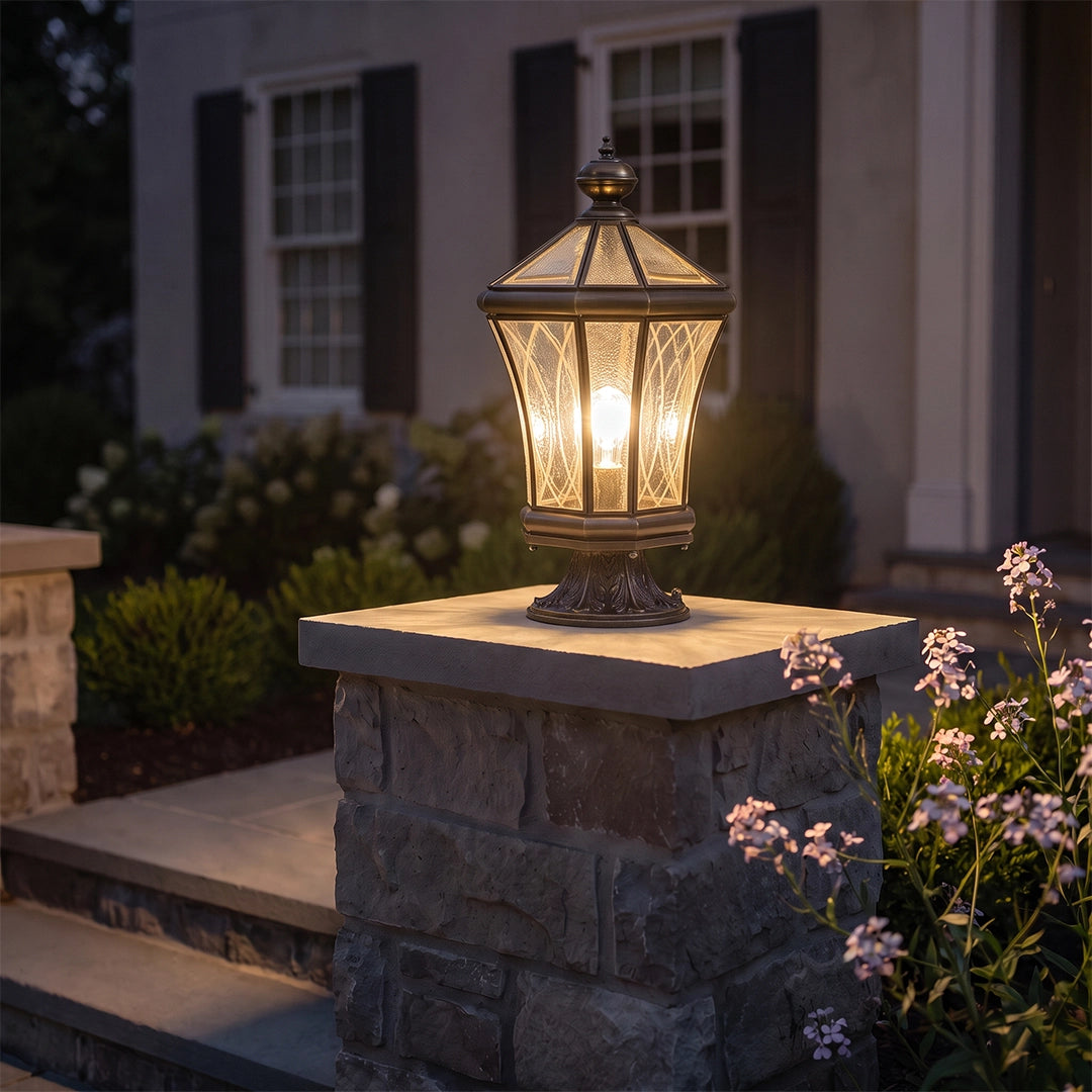 Vintage solar pillar lantern with warm glow on stone column beside front porch