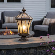 Vintage solar pillar lantern with warm glow beside outdoor fire pit and patio seating