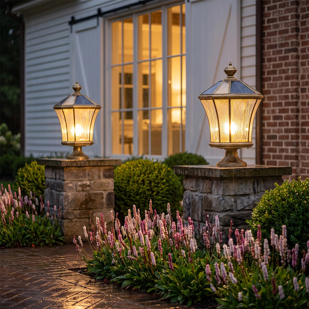 Vintage solar pillar lanterns with warm glow on stone columns beside flower garden