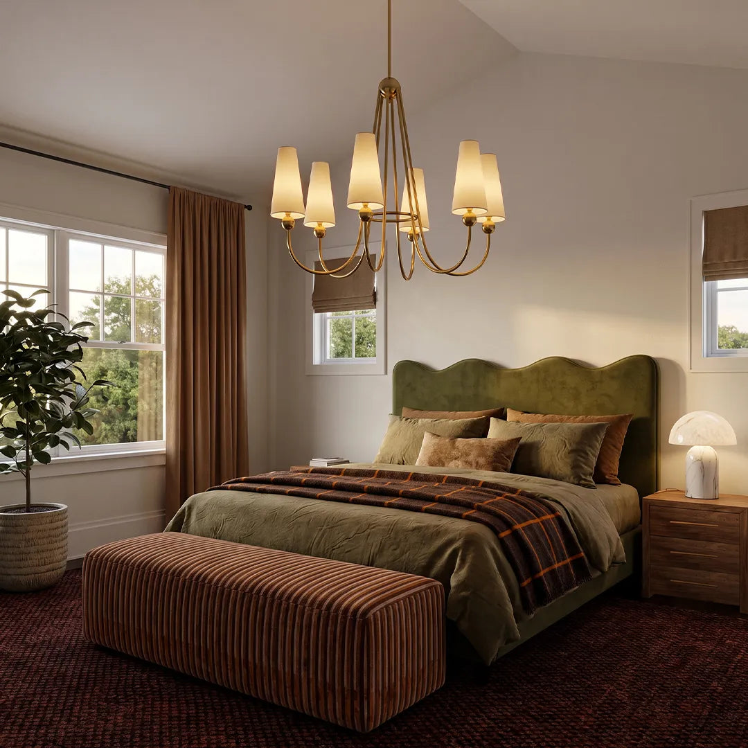 Vintage solid brass chandelier hanging above a cozy bedroom with an upholstered bed and warm neutral decor.