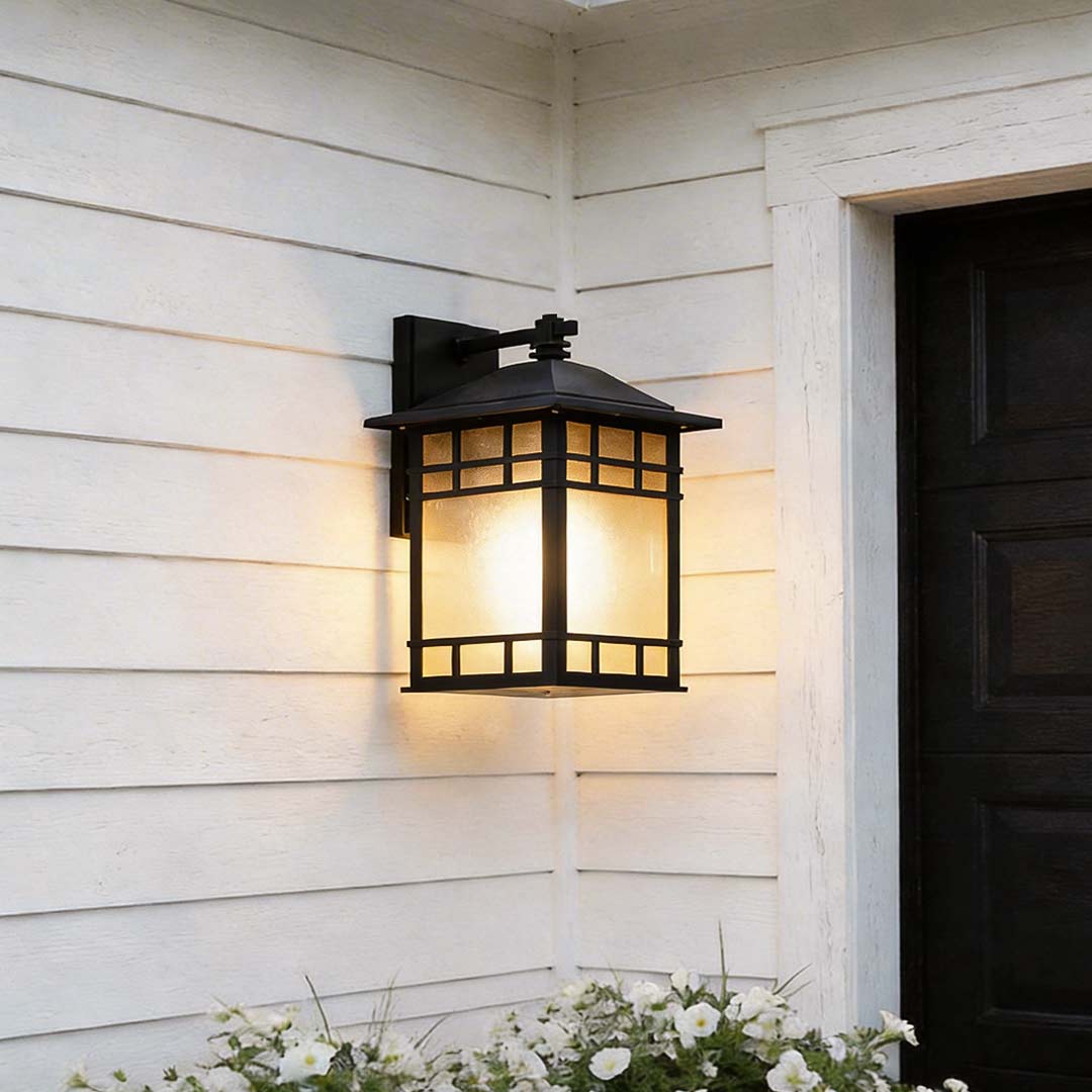 Vintage wall lantern with a black metal frame, providing warm illumination beside a white door.