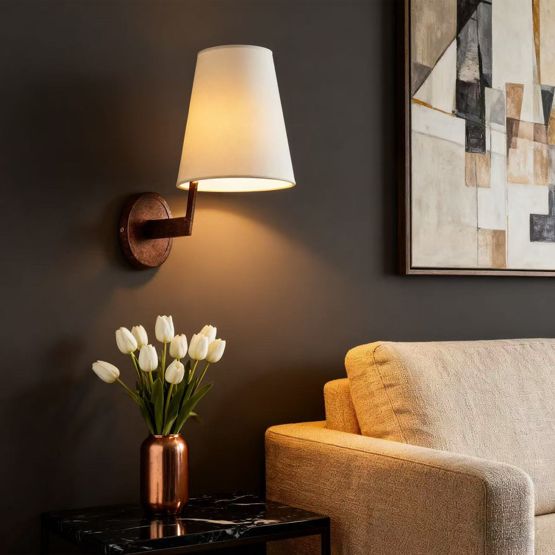 Vintage wall lights illuminating dark accent wall beside artwork with warm glow from fabric shade creating cozy ambiance