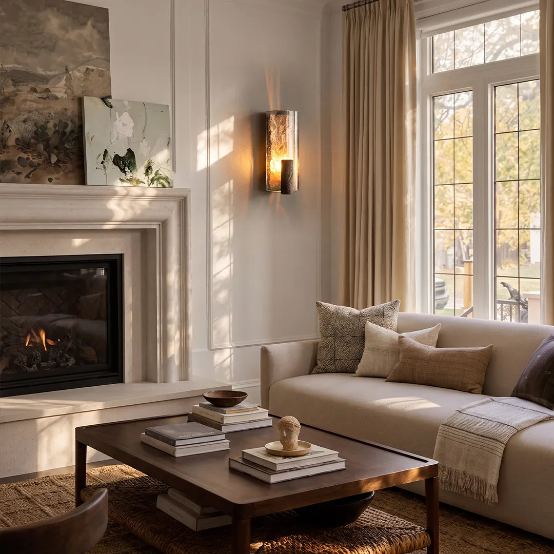 Vintage wall sconce light mounted beside a fireplace window in a bright living room with soft warm glow.