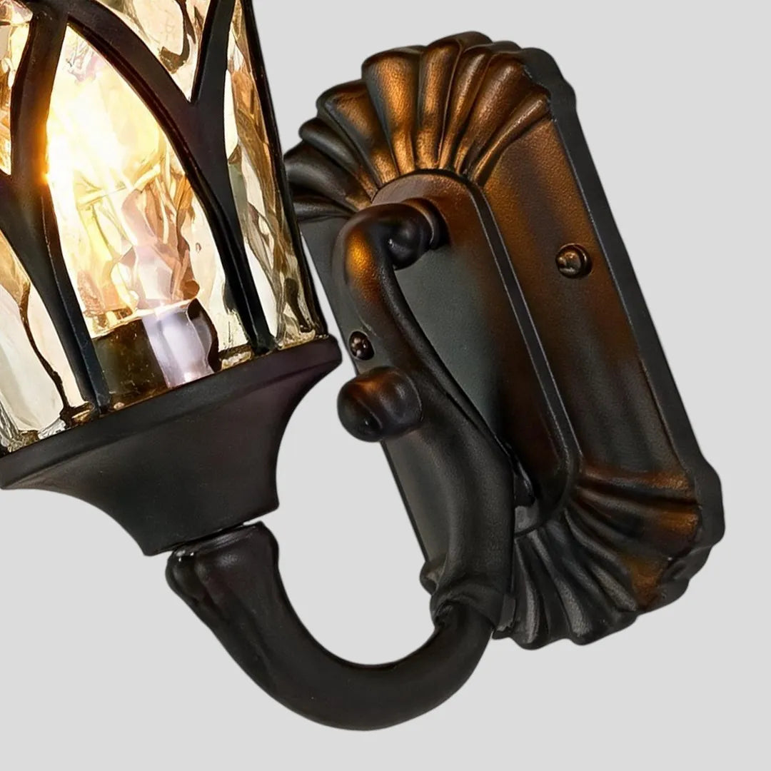 Vintage wall sconce light fixtures close-up showing the ornate bronze backplate and curved mounting arm.