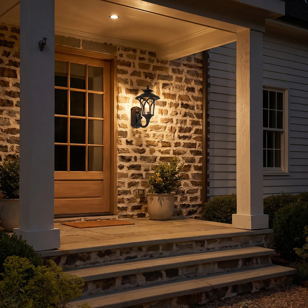 Vintage wall sconce light fixtures illuminating a covered brick porch with warm traditional lighting.