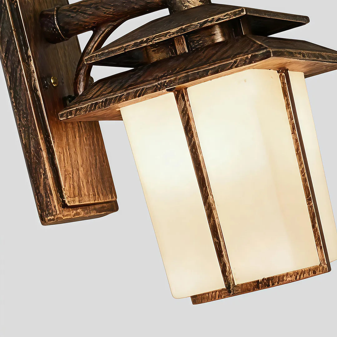 Vintage wall sconce light fixtures close-up showing the antique bronze finish and softly glowing glass panels.
