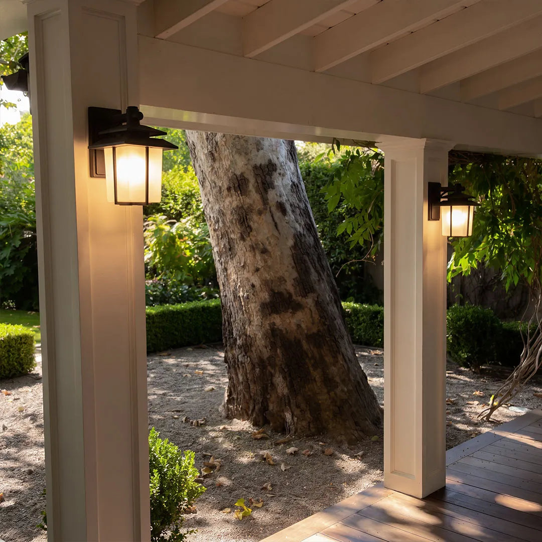 Vintage wall sconce light fixtures installed on outdoor columns to illuminate a covered walkway.