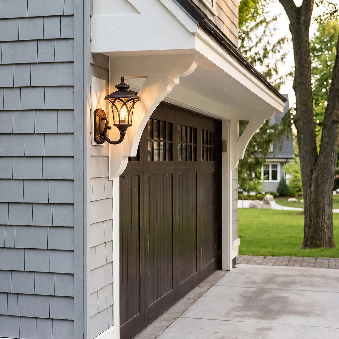 Vintage wall sconce light fixtures mounted beside a garage door on a classic white exterior.