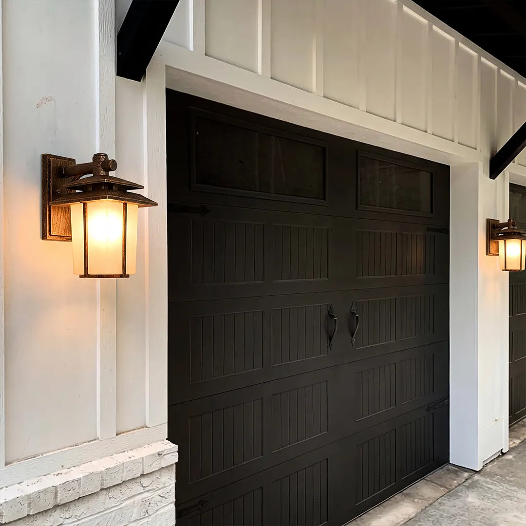 Vintage wall sconce light fixtures installed beside a garage door for warm exterior illumination.