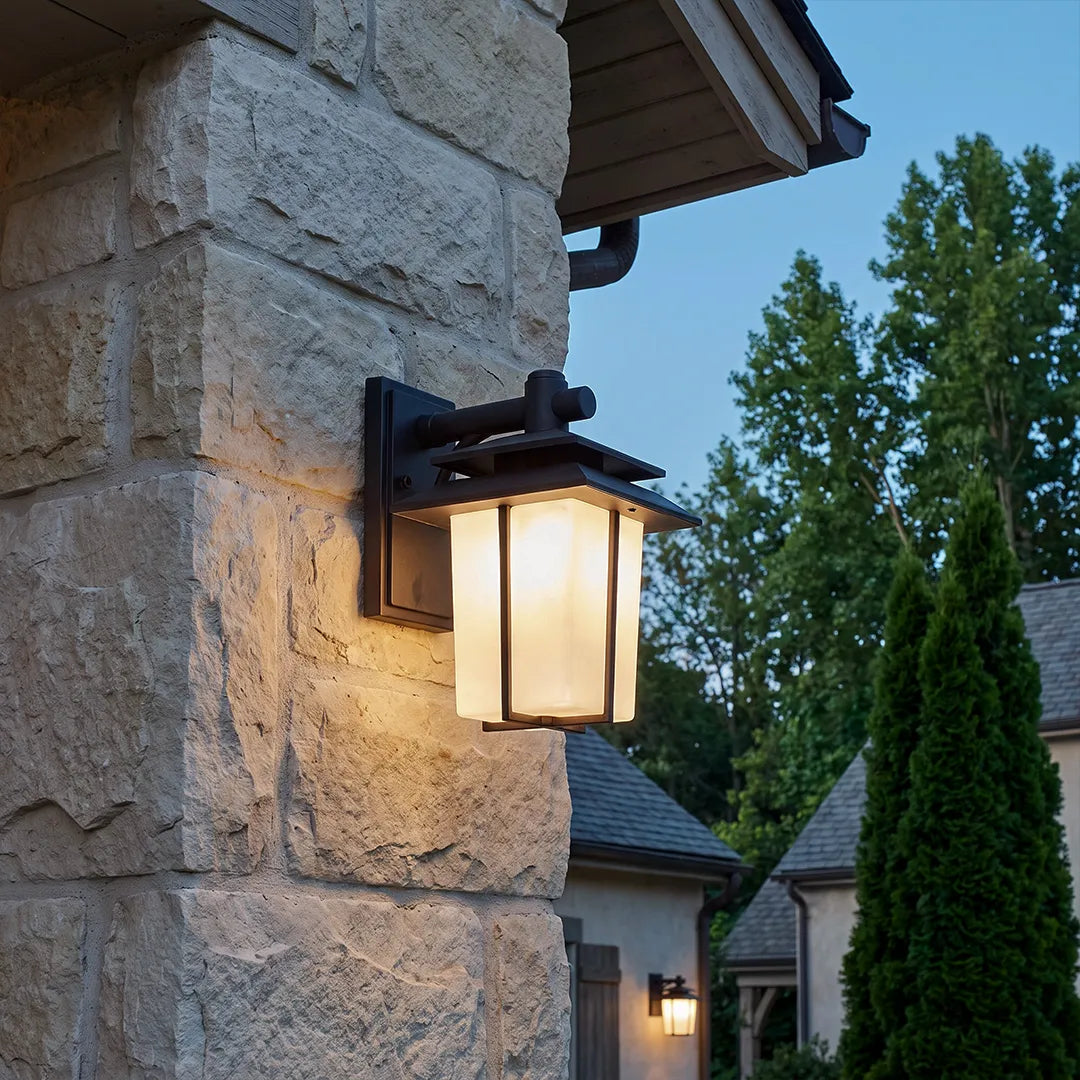 Vintage wall sconce light fixtures mounted on a stone exterior wall for warm entryway lighting.