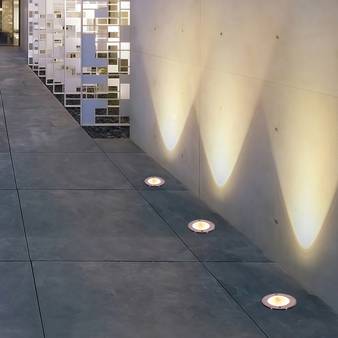 Row of bright inground light fixtures illuminating an exterior wall for a clean architectural look.