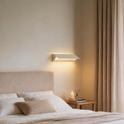 Wall adjustable light installed above bed providing soft ambient bedroom lighting.