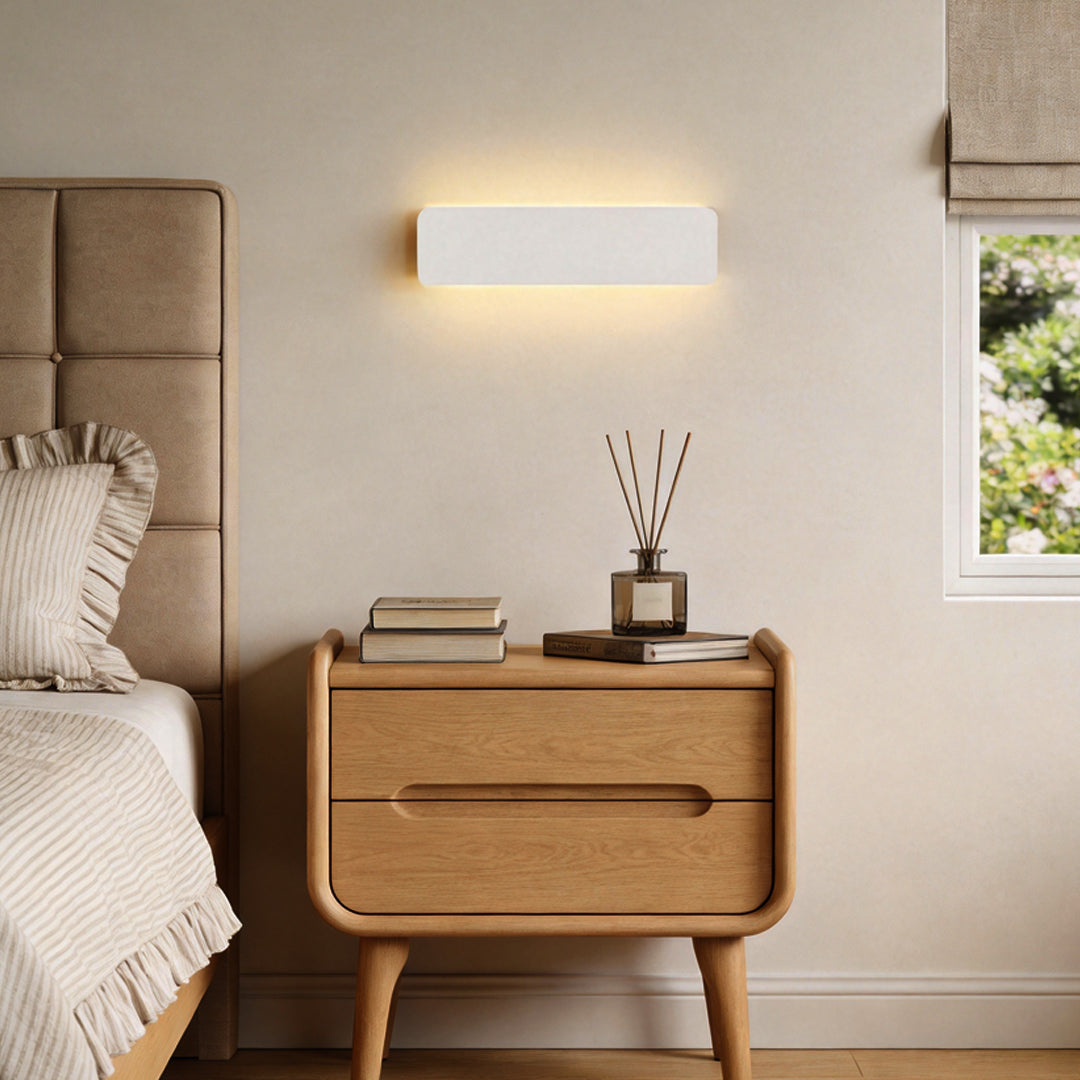 Modern wall adjustable light mounted above bedside table in minimalist bedroom.