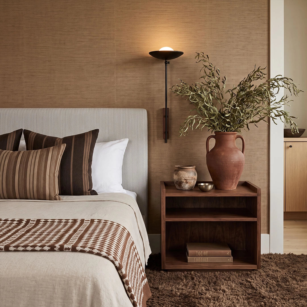 Wall adjustable light installed above a bedside table in a cozy brown bedroom.