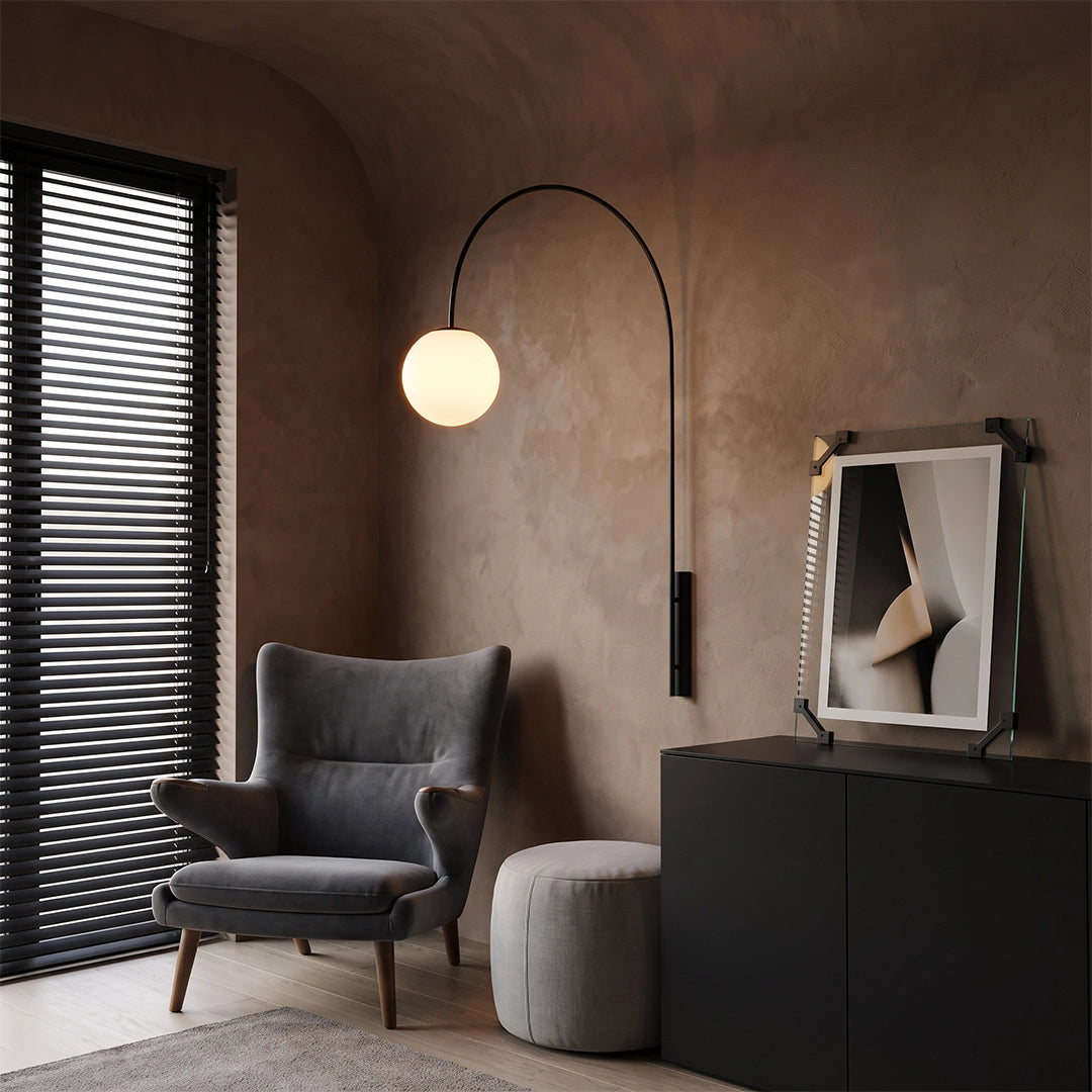 Wall arm light with an arched black frame and glowing globe shade illuminating a cozy reading corner.