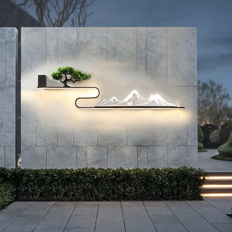 Close-up of wall art with light, showcasing a mountain and tree silhouette with warm illumination.
