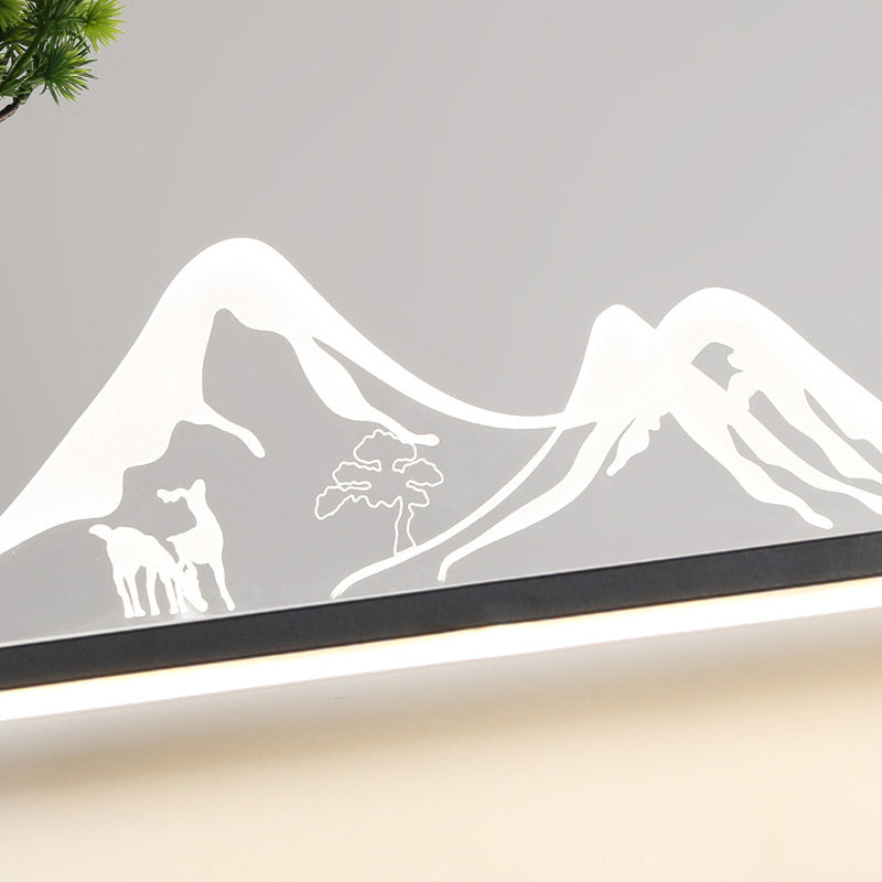 Wall art with light with a mountain and tree silhouette, providing ambient lighting.