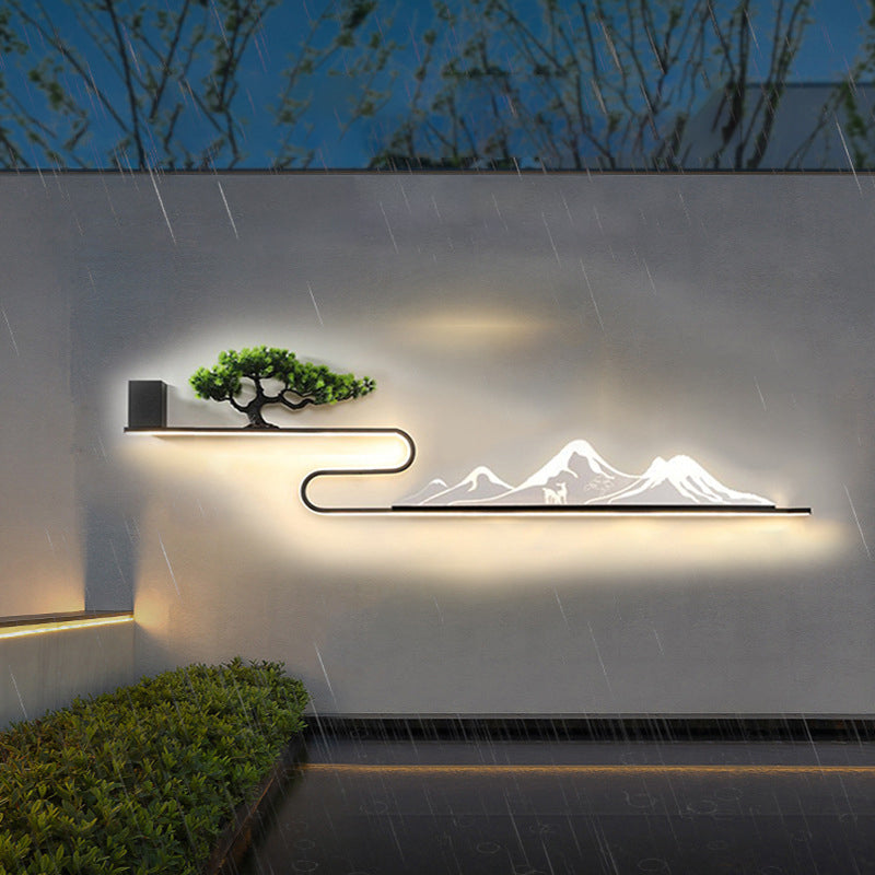 Wall art with light showcasing a mountain and tree design, illuminated at night.