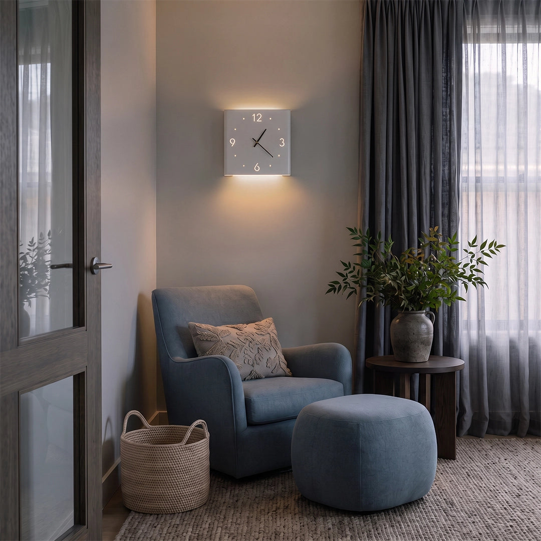 Wall clock lamp glowing above a blue armchair in a cozy corner with sheer curtains.